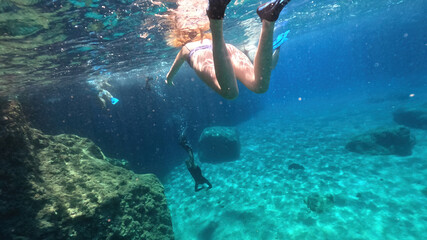 Underwater split photo of woman diver, snorkelling in beautiful paradise volcanic white rock famous Kleftiko with emerald crystal clear sea and caves, Milos island, Cyclades, Greece