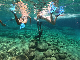 Underwater split photo of woman diver, snorkelling in beautiful paradise volcanic white rock famous...