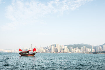 Obraz premium Traditional Chinese Junkboat sailing. Views of the skyscrapers background.
