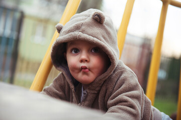 Mały chłopiec w misiowej bluzie na placu zabaw