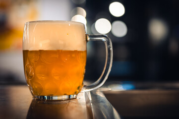 Cold beer glass on a bar or pub desk. Tasty fresh yellow beer of Czech Republic. Dark pub on background.