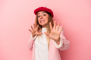 Young Russian woman isolated on pink background indicates with both fore fingers up showing a blank...