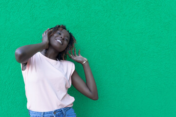 Fototapeta premium The concept of lifestyle and people - a smiling African-American young woman listening to music with headphones. The joy and emotions of a person