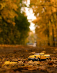 a small yellow model of an old car against the background of an autumn yellow landscape. High...