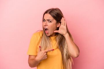 Young Russian woman isolated on pink background blink at the camera through fingers, embarrassed covering face.