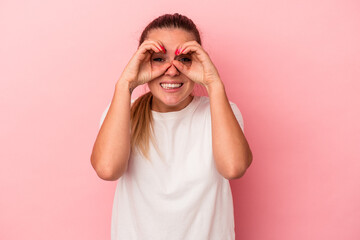 Young Russian woman isolated on pink background showing okay sign over eyes