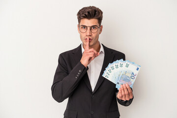 Young business caucasian man holding banknotes isolated on white background keeping a secret or...