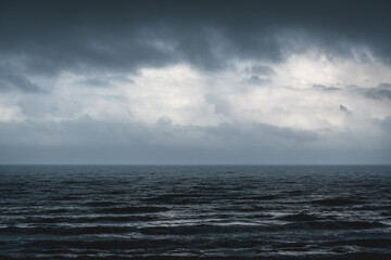 Melancholic dark blue seascape with silver shining waves during storm