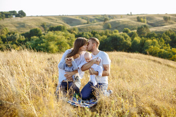 Fototapeta na wymiar mom dad and two sons posing on the background of nature in a field with tall grass