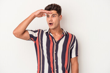 Fototapeta premium Young caucasian man isolated on white background looking far away keeping hand on forehead.