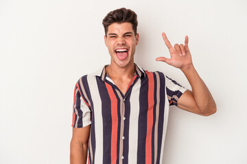 Naklejka premium Young caucasian man isolated on white background showing a horns gesture as a revolution concept.