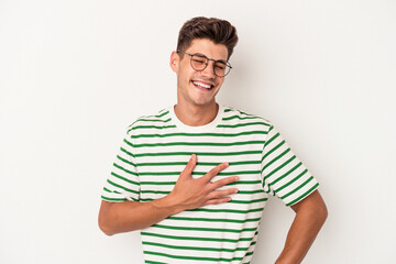 Obraz premium Young caucasian man isolated on white background laughing keeping hands on heart, concept of happiness.