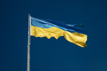 Large national flag of Ukraine flies in the blue sky