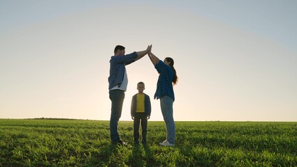 Happy family dreams of their own house in park in summer in sun. Family game. Children mom and dad are building house together with their own hands at sunset. Caring for children by parents