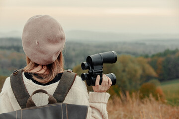 Style girl with binoculars and backpack at countryside