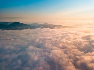 Fototapeta na wymiar High flight over the fog in the mountains. Ukrainian Carpathians in the morning. Aerial drone view.