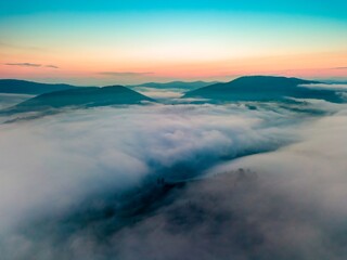Fog in the mountain valley at dawn. Ukrainian Carpathians in the morning in the haze. Aerial drone...