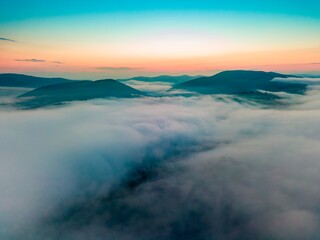 Fototapeta premium Fog in the mountain valley at dawn. Ukrainian Carpathians in the morning in the haze. Aerial drone view.