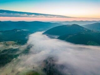 Fototapeta na wymiar Fog in the mountain valley at dawn. Ukrainian Carpathians in the morning in the haze. Aerial drone view.