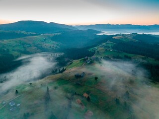 Fog in the mountain valley at dawn. Ukrainian Carpathians in the morning in the haze. Aerial drone view.