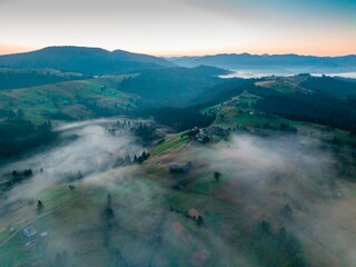 Fog in the mountain valley at dawn. Ukrainian Carpathians in the morning in the haze. Aerial drone...