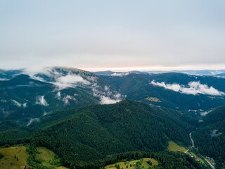 High flight among the clouds at dawn. Ukrainian Carpathians in the morning in the haze. Aerial drone view.