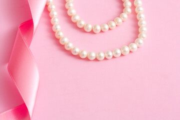 A beautiful pearl necklace on pink background. Blank copy space for own text.
