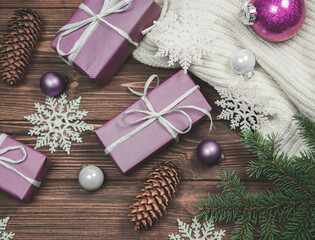 Christmas composition fir branches, gift boxes, glass balls,  jumper white knitted, cones on a wooden background.