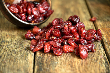 Dried cranberries in a ceramic bowl on a wooden old table.