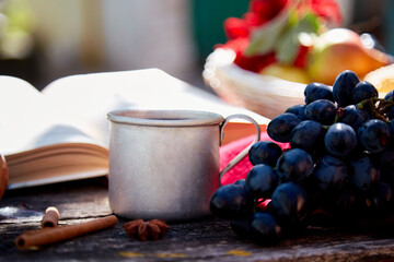 Cozy autumn concept with mug of tea, vintage book, apples in rustic style. Autumn aesthetic still life with shadows, red dahlia. Cozy home, warm scarf and tea. Thanksgiving Day concept.