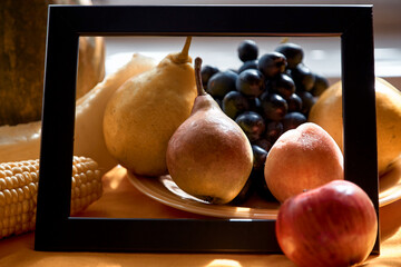 Creative fruits photography: frame of grapes, apple, pear, peach, corn and melon on the orange...