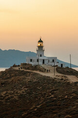 Fototapeta na wymiar Lighthouse on the Coastline at Sunset in Mykonos Greece