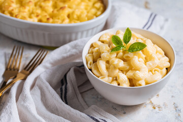 Mac and cheese with basil on top on a rustic wooden board