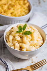 Mac and cheese with basil on top on a rustic wooden board