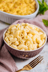 Mac and cheese with basil on top on a rustic wooden board