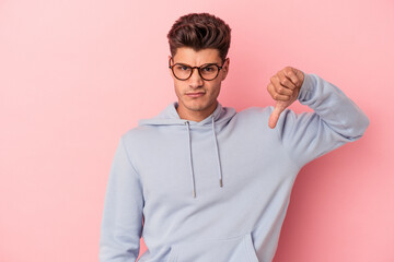 Young caucasian man isolated on pink background showing thumb down, disappointment concept.