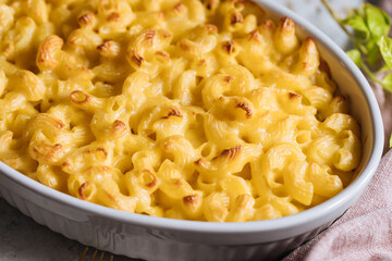 Mac and cheese with basil on top on a rustic wooden board