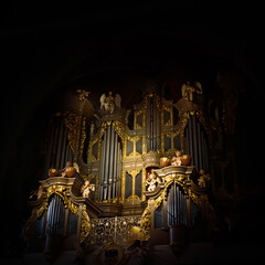 Musical instrument organ with figurines of angels and rays of light as background.