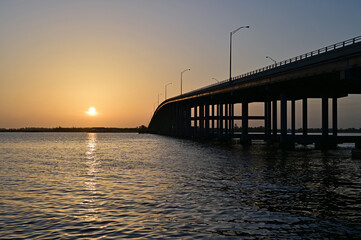 Fototapeta na wymiar Rickenbacker Causeway Bridge in Miami, Florida under orange sky as sun rises.