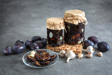 Home preparations for the winter. Dried plums with garlic in oil. Healthy diet. Dark gray background. Autumn preparations.