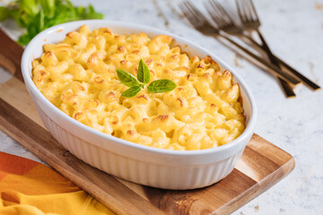 Mac and cheese with basil on top on a rustic wooden board