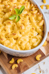 Mac and cheese with basil on top on a rustic wooden board