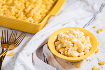 Mac and cheese with basil on top on a rustic wooden board