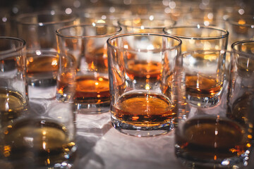 Beautiful row of different colored alcohol drinks on a party, whiskey, scotch whisky, bourbon, cognac, brandy and other cocktails, glasses on a bar counter table