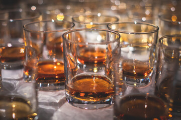 Beautiful row of different colored alcohol drinks on a party, whiskey, scotch whisky, bourbon, cognac, brandy and other cocktails, glasses on a bar counter table