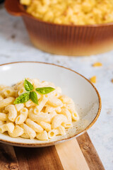 Mac and cheese with basil on top on a rustic wooden board