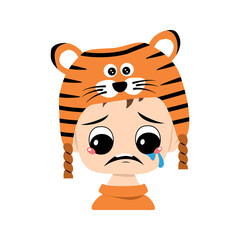 Boy with big eyes and depressive emotion, crying, tears face in tiger hat. Cute kid with sad face in a festive costume for New Year, Christmas and holiday. Head of adorable child with emotions