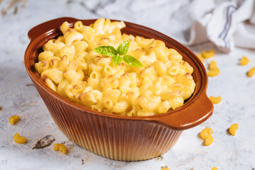 Mac and cheese with basil on top on a rustic wooden board