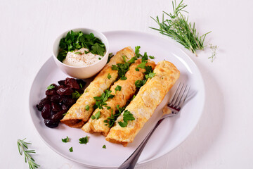 Egg rolls with filling on a white plate on a white table