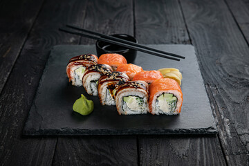 Japanese cuisine. Rolls on a square plate on a black table
